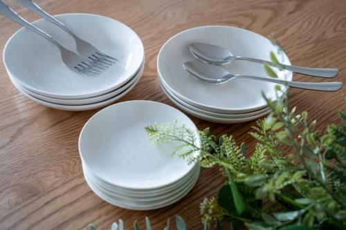 three white plates and forks and spoons on a table at Mks 101 in Wada