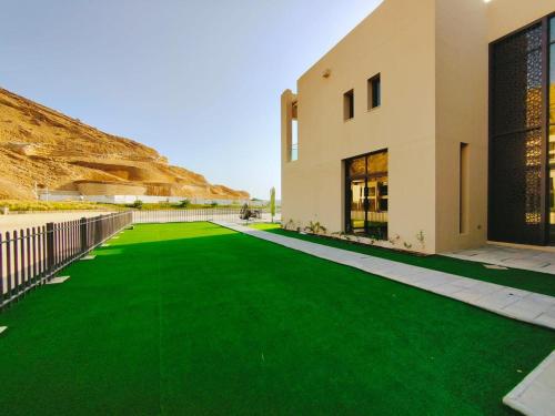 a house with a green lawn next to a building at Nameer bay in Bandar Jişşah