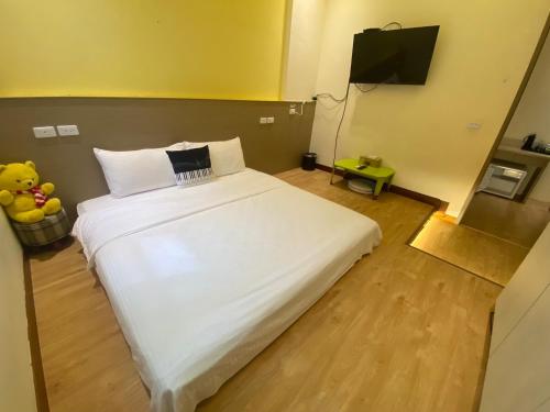 a bedroom with a large white bed and a television at 觀關嚮戶民宿 臺東縣民宿1214號 in Guanshan