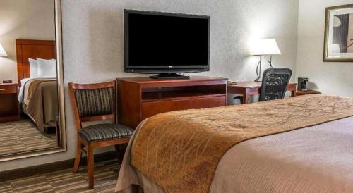 a hotel room with a bed and a flat screen tv at Comfort Inn & Suites University South in Ann Arbor