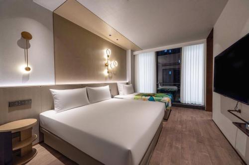 a bedroom with a large white bed and a television at Novotel Kunshan East in Kunshan