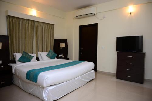a bedroom with a large bed and a flat screen tv at Citrus plaza in Bengaluru