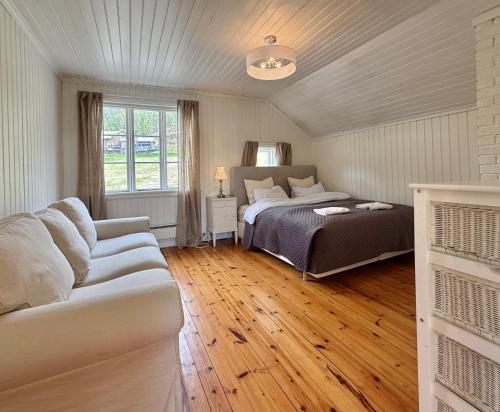 a bedroom with a bed and a couch at Feriehus ved Nisser med egen strand, brygge, peis og robåt til fri bruk in Kyrkjebygdi