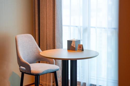 a table and a chair next to a window at Novotel Kunshan East in Kunshan