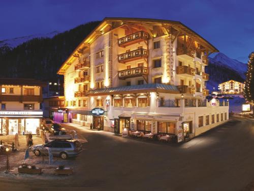 a large building with a car parked in front of it at Hotel Post Sport- und Wellness in Samnaun