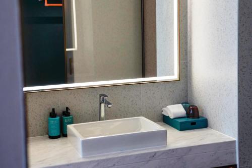 a white sink in a bathroom under a mirror at Novotel Kunshan East in Kunshan