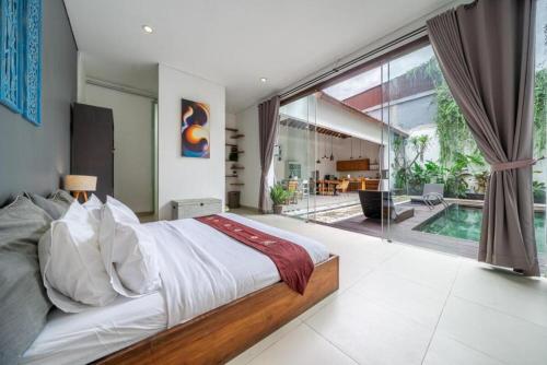 a bedroom with a large bed and a swimming pool at Modern Tropical 2BR Villa in Seminyak Kuta with Pool & Garden in Legian