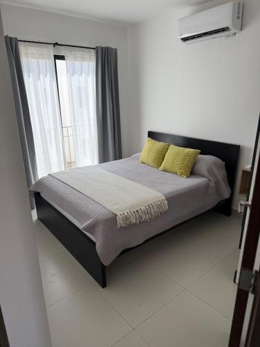 a bedroom with a bed with yellow pillows and a window at Take A Break in El Suazal