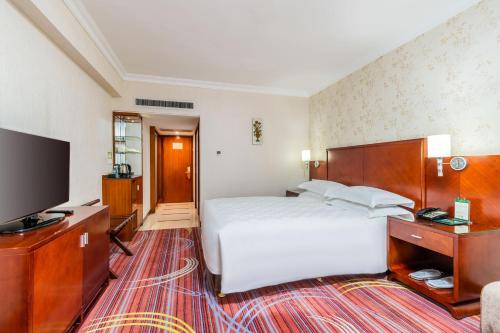 a hotel room with a bed and a flat screen tv at Guangzhou Hutian Hotel in Guangzhou