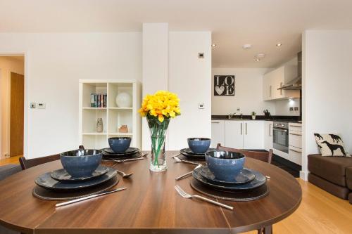 a dining room table with a vase of yellow flowers at ALTIDO Lovely 1-Bed Flat near 02 Arena in London