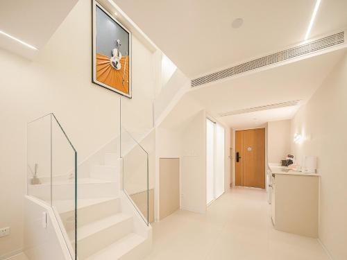 a white staircase in a house with a picture on the wall at Ouchen International Sky River Hotel (Monument to the people's Liberation Pedestrian Street Store, Chongqing) in Chongqing