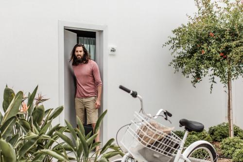 a man standing in a doorway next to a bike at Casa Cook Rhodes (Adults Only) in Kolymbia