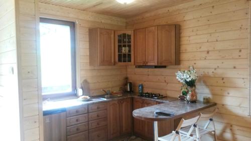 cocina con armarios de madera, mesa y ventana en Chalet TysaBorkut en Kvasy