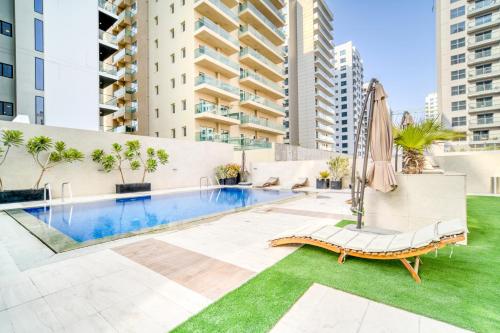 an outdoor swimming pool with an umbrella and a chaise lounge at Stella Stays Lana Tower in Dubai