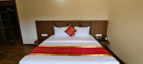 a bed in a hotel room with two pillows at CKM- Lake View Mountain View and Pool in Chikmagalūr