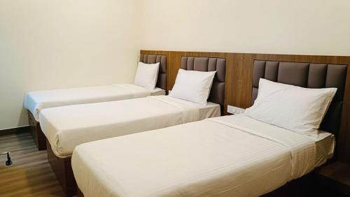 two beds in a hotel room with white sheets at CKM- Lake View Mountain View and Pool in Chikmagalūr