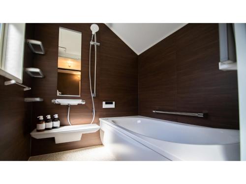 ein Badezimmer mit Badewanne und Waschbecken in der Unterkunft Kominka Hotel kurasu - Vacation STAY 24275v in Tatsuno