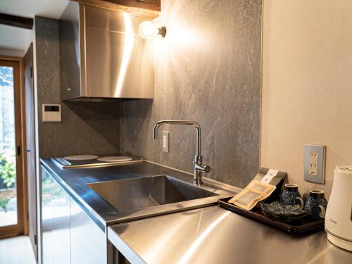 a kitchen with a stainless steel sink and a counter at Kominka Hotel kurasu - Vacation STAY 93210v in Tatsuno