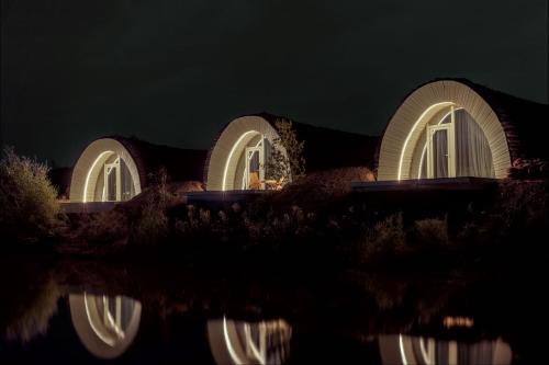 a building lit up at night with reflections in the water at Agropensiune WakePark Eco Hotel 