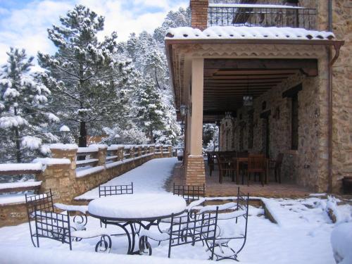 a covered patio with tables and chairs in the snow at Hotel de Montaña Cueva Ahumada in Villaverde de Guadalimar