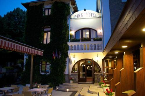 a hotel with tables and chairs in front of a building at Hotel Park Hévíz in Hévíz