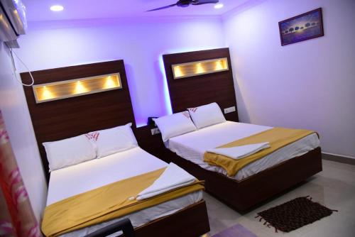 two beds in a room with purple lights at HoTEL APPLE GRAND in Vijayawāda