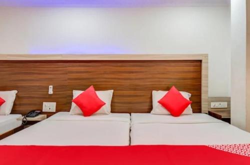 a bedroom with two beds with red and white pillows at HoTEL APPLE GRAND in Vijayawāda