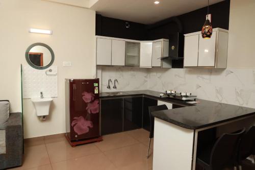 a kitchen with white cabinets and a black counter top at Grace Apart Hotel @Kochi in Cochin