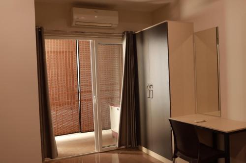 a room with a desk and a sliding glass door at Grace Apart Hotel @Kochi in Cochin