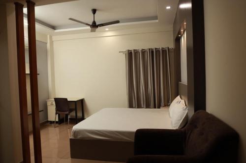 a bedroom with a bed and a chair and a desk at Grace Apart Hotel @Kochi in Cochin