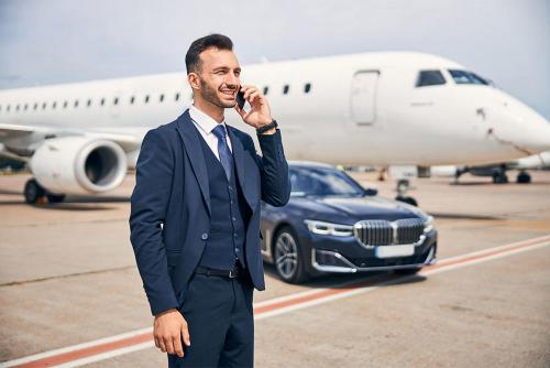a man in a suit talking on a cell phone next to an airplane at Airport Transport Service Raleigh NC in Morrisville