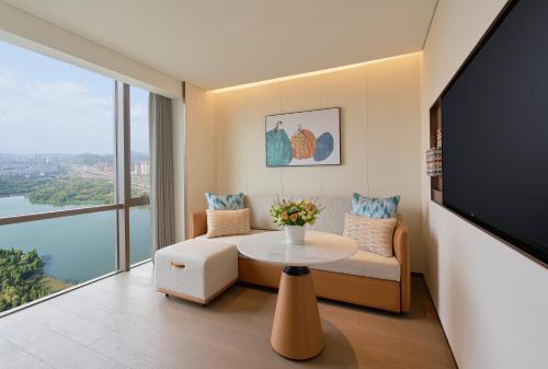 a living room with a table and a tv at Hyatt Place Kunming South Railway Station in Kunming