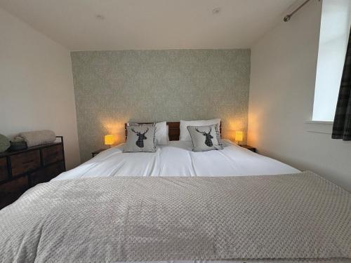 Un dormitorio con una gran cama blanca con dos almohadas. en Muirside Cottage, en Stirling