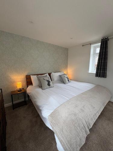 a bedroom with a large white bed with a window at Muirside Cottage in Stirling