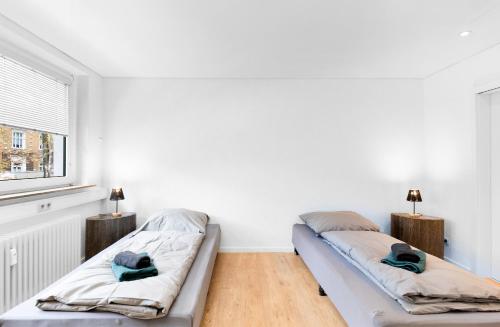 a white room with two beds and a window at 24-7 Living - Unna Central City Apartments in Unna