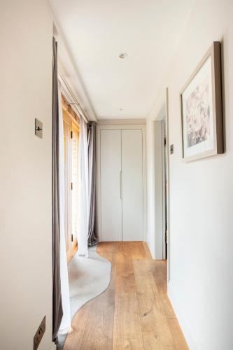 a hallway with white walls and wood floors and a mirror at Cosy Barn Conversion - peaceful, private double room in Shenfield