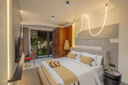 a bedroom with a large white bed and a chair at Palermo Suites Ubud in Ubud