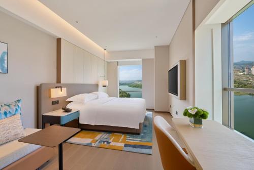 a hotel room with a bed and a desk and a room with a view at Hyatt Place Kunming South Railway Station in Kunming