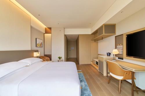a hotel room with a large bed and a desk at Hyatt Place Kunming South Railway Station in Kunming