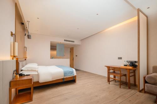 a bedroom with a bed and a table and a desk at Huazhu Yiye Jiyu Hotel in Shanghai