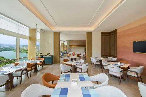 a restaurant with tables and chairs with a view at Hyatt Place Kunming South Railway Station in Kunming