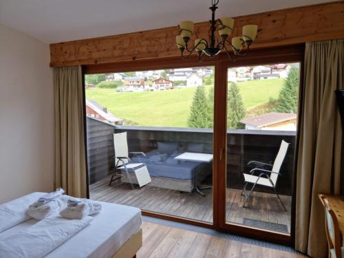 a bedroom with a view of a patio with a bed and a couch at Wellness Aparthotel Panorama Alpin - Ferienwohnungen Jerzens im Pitztal in Jerzens