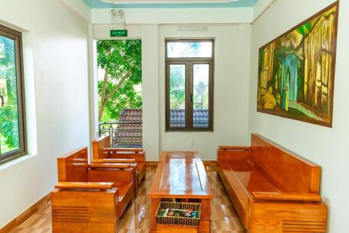 a room with wooden tables and chairs and windows at Phong Nha Cherish Homestay in Bố Trạch