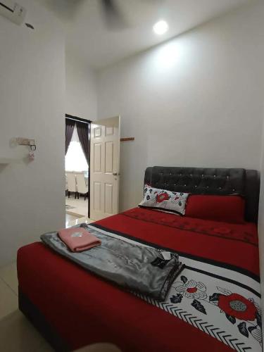 una camera da letto con un letto con lenzuola rosse e un computer portatile rosso sopra di Homestay Kayangan Gua Musang a Gua Musang