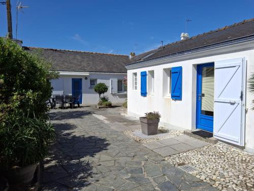 a white building with blue doors and a patio at Maison au calme proche commerces et plages in Gâvres