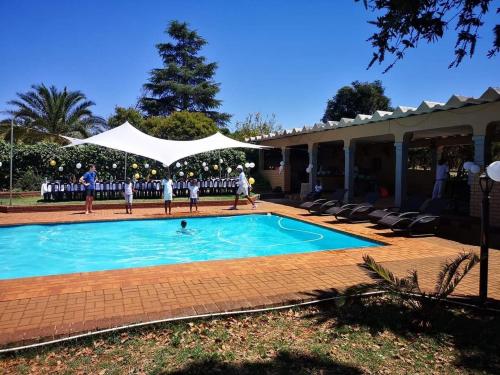 a group of people standing around a swimming pool at Aloe Tree Guest House in Krugersdorp