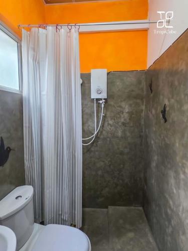 a bathroom with a white shower curtain and a toilet at Lake View Resort by TropiCube in Pamunugama