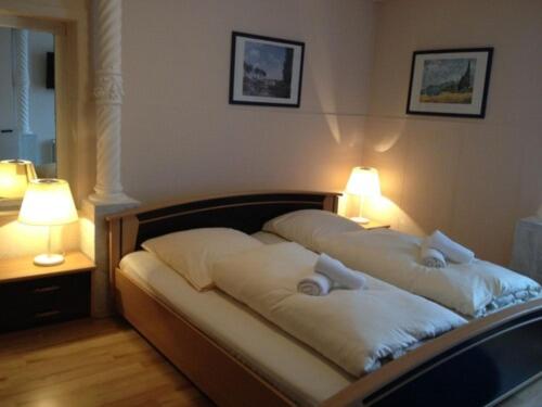 a bed with two pillows on it with two lamps at Hotel Mina in Hemmingen