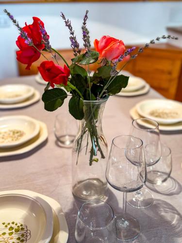 a vase of flowers on a table with plates and glasses at Casa Altolaterra in Tagliacozzo