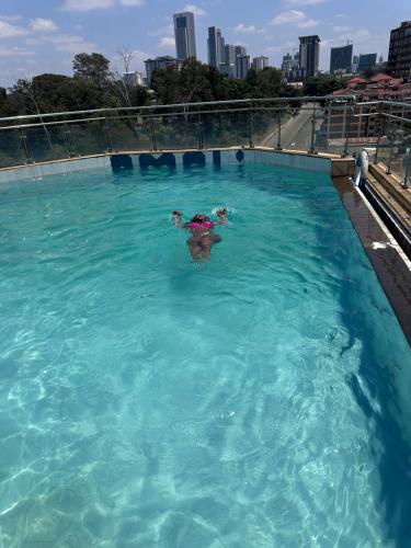 eine Person, die in einem großen Schwimmbecken schwimmt in der Unterkunft Yallo Residency in Nairobi